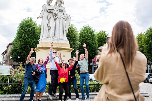 Eine Gruppe von Besuchern posiert vor der Statue auf dem Marktplatz in Maaseik, in der Nähe des Büros von Visit Maaseik