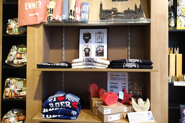 A wooden shop shelf with T-shirts, candles, souvenirs and regional products.