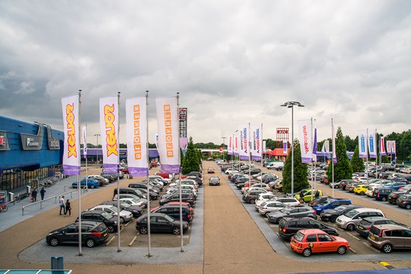 Auto's geparkeerd voor het retailpark Roermond met een donkere, dreigende lucht op de achtergrond