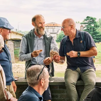 Vier mannen tijdens een aperitiefwandeling in Maaseik, terwijl een gids onderweg een lokale lekkernij laat proeven.