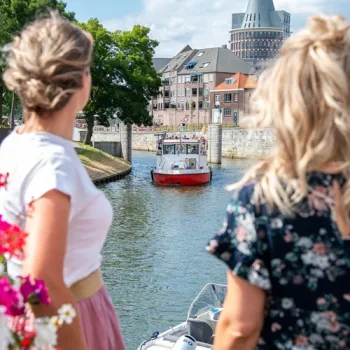 Twee vrouwen kijken uit over de Roer terwijl de rondvaart boot aan het binnenvaren is om aan te meren.